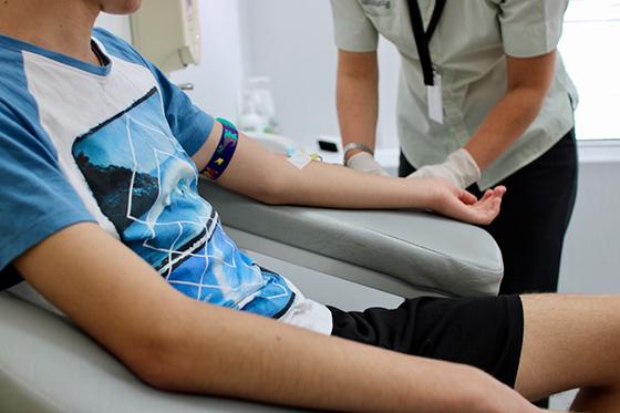 图为一名护士正在照料一名身穿蓝色t恤的男孩前臂上的静脉注射.