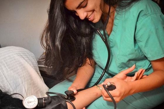 一名穿着绿色工作服的护士用听诊器给病人量血压. 