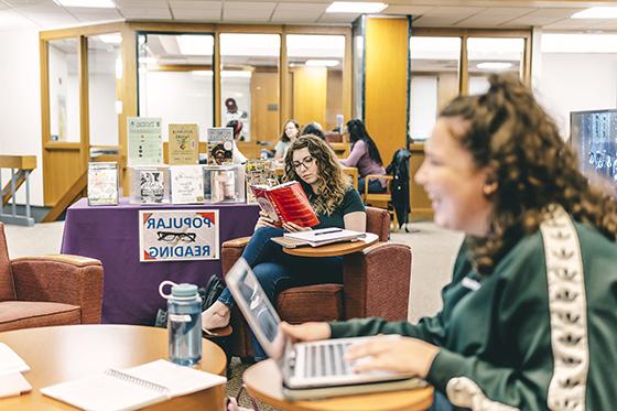 图为波胆网站的学生们聚集在珍妮·梅隆·金图书馆, 坐在椅子和桌子上，一边用笔记本电脑工作，一边看书. 