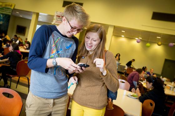 两名波胆网站的学生微笑着一起看手机的照片